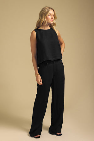 A woman wearing a black sleeveless top and black wide-leg NATALEN LINEN PANT.