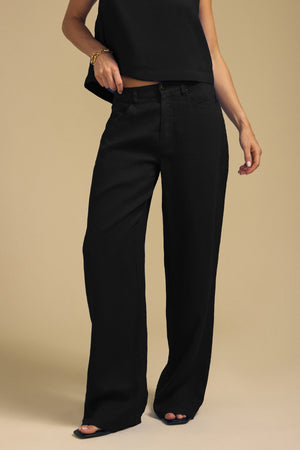 Person wearing a sleeveless black top and NATALIE LINEN PANT wide-leg linen pants with an elastic waistband.