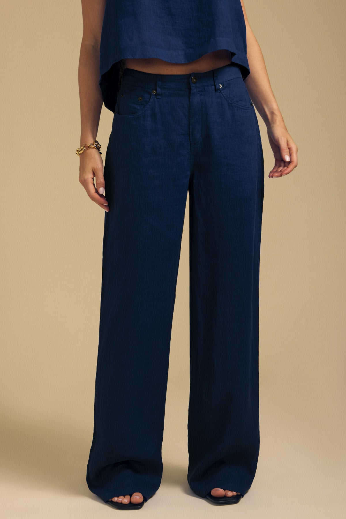 A person wearing dark blue NATALIE LINEN PANT wide-leg linen pants with an elastic waistband and a matching cropped top.-46422215590081