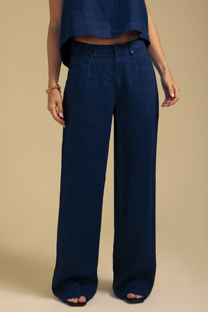 A person wearing dark blue NATALIE LINEN PANT wide-leg linen pants with an elastic waistband and a matching cropped top.