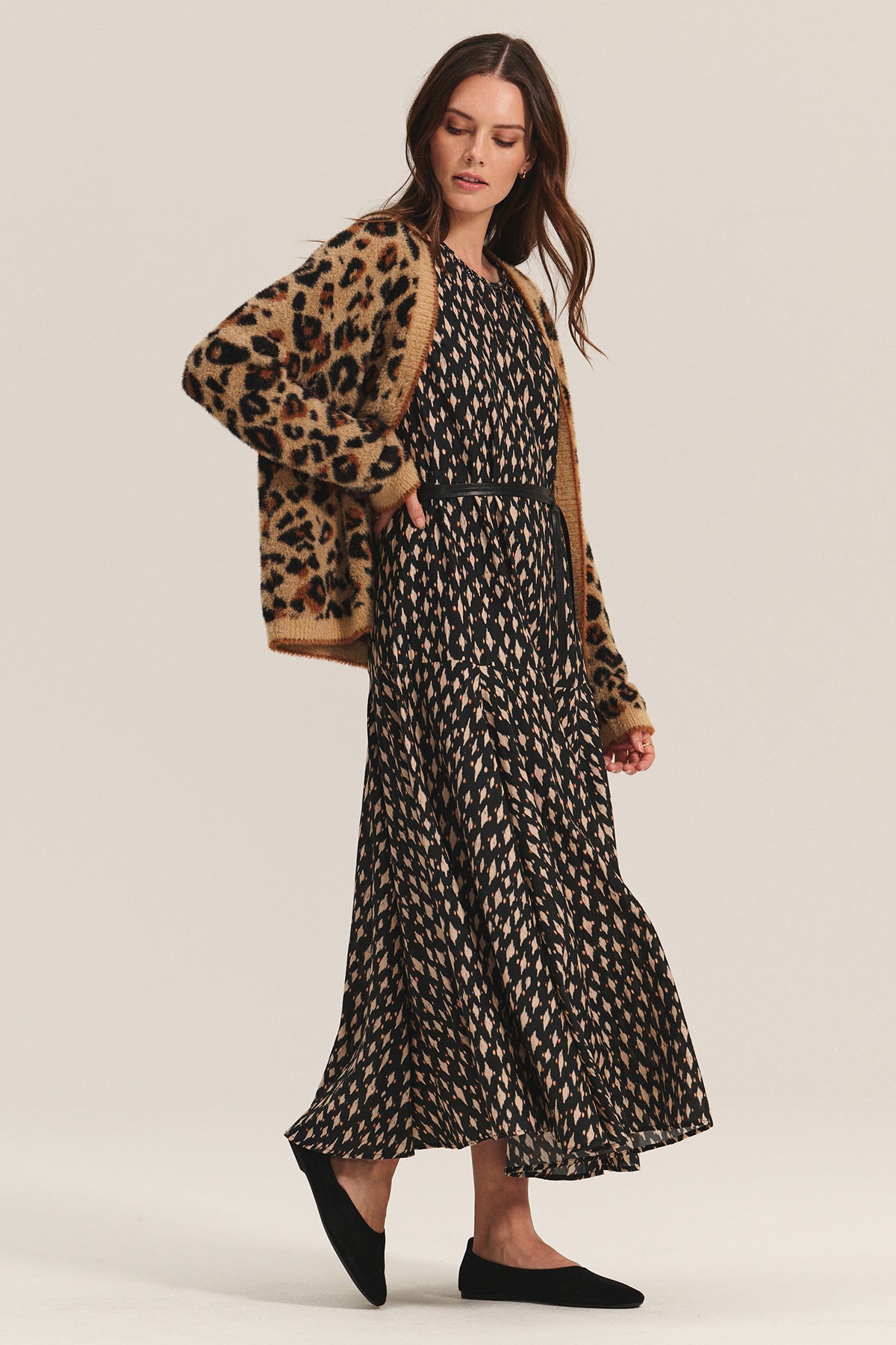 A woman wears the KAITLYN DRESS by Velvet by Graham & Spencer, a long silk cotton voile dress with a detachable black belt, styled with a leopard print cardigan and black flats against a light background.