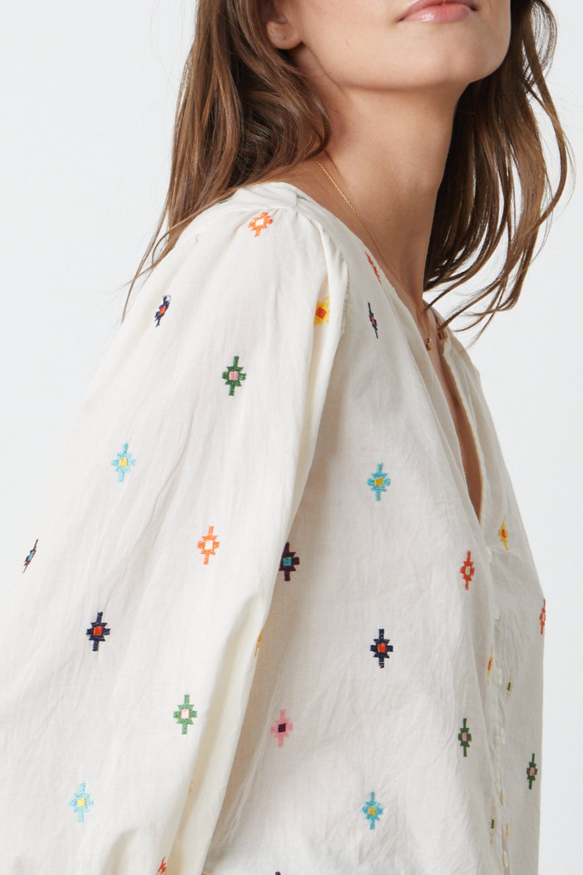   The model is wearing a white Velvet by Graham & Spencer blouse with multi - colored embroidery close up detail 