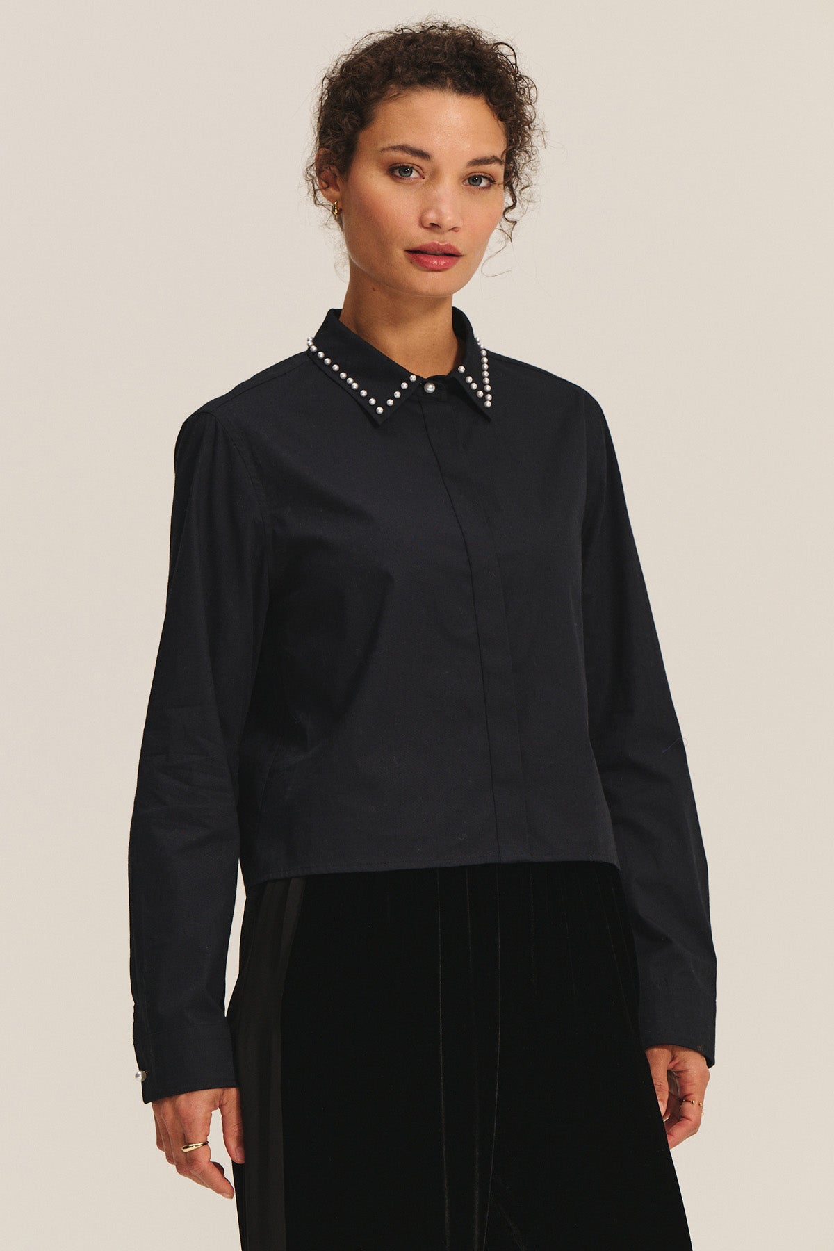 A woman wears the JOCELYN SHIRT by Velvet by Graham & Spencer, featuring a black beaded collar and long sleeves, standing against a plain background.