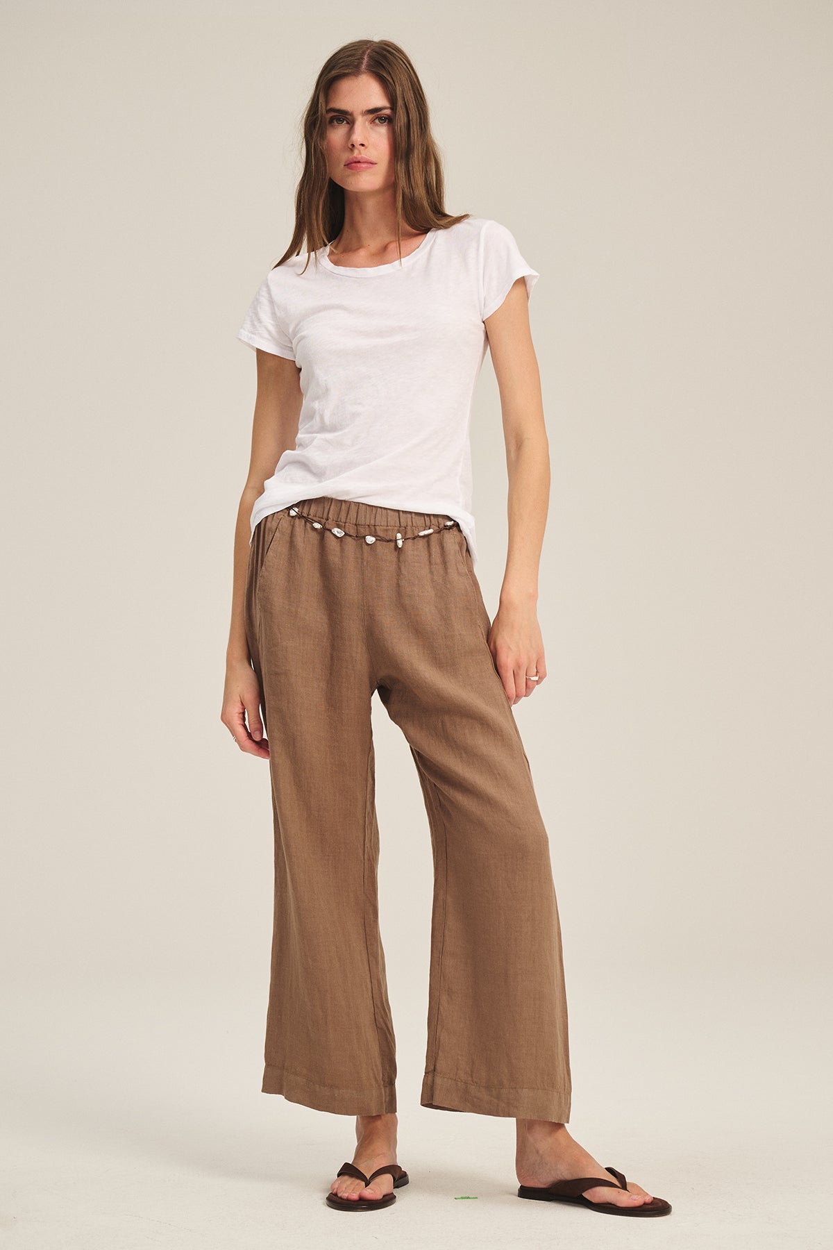 A woman stands against a plain background wearing Velvet by Graham & Spencer's LOLA LINEN PANT.-39582119624897