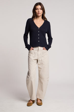 A woman faces forward in the Velvet by Graham & Spencer OTTILIE CARDIGAN, paired with light beige wide-leg pants and brown flats against a plain background.