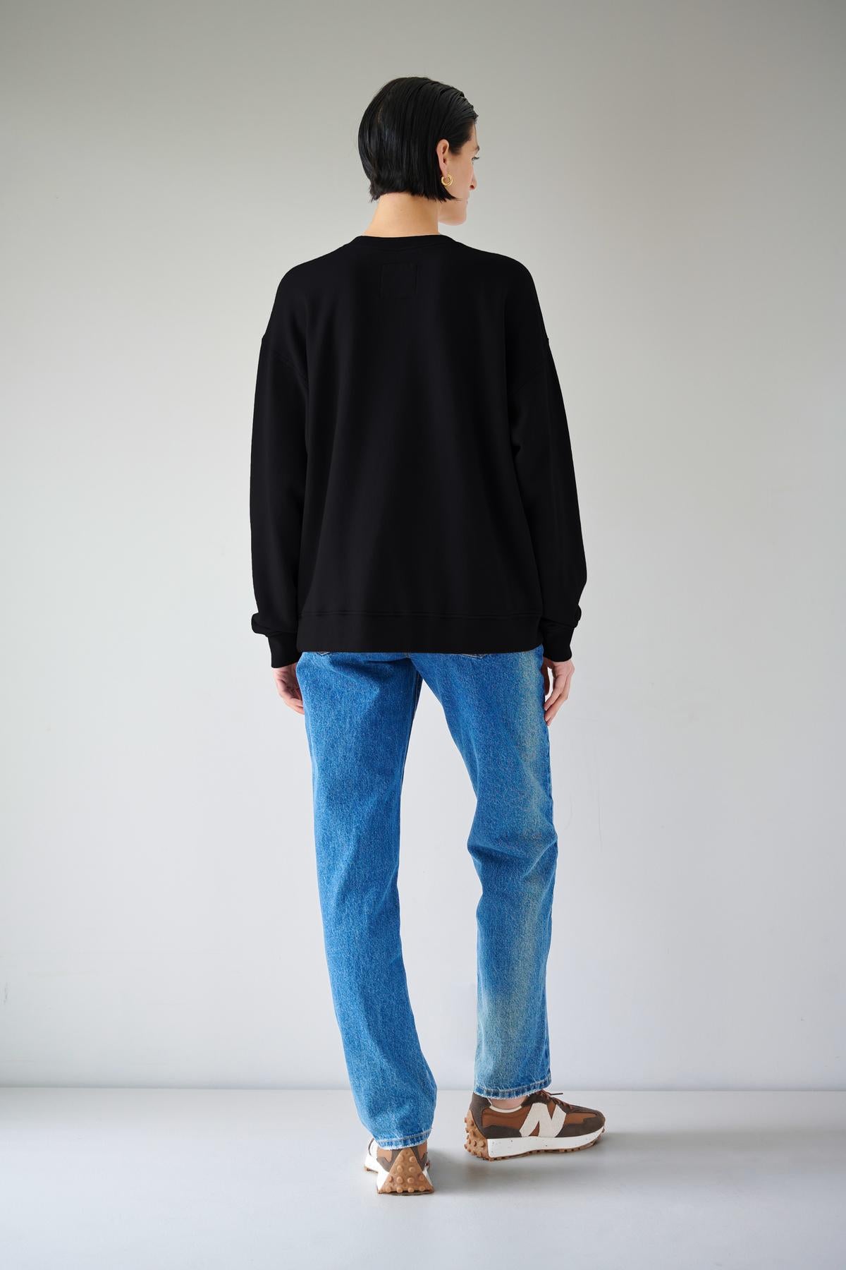 The slouchy back view of a woman rocking organic cotton jeans and an Abbot sweatshirt from Velvet by Jenny Graham with styling versatility.-35190150365377