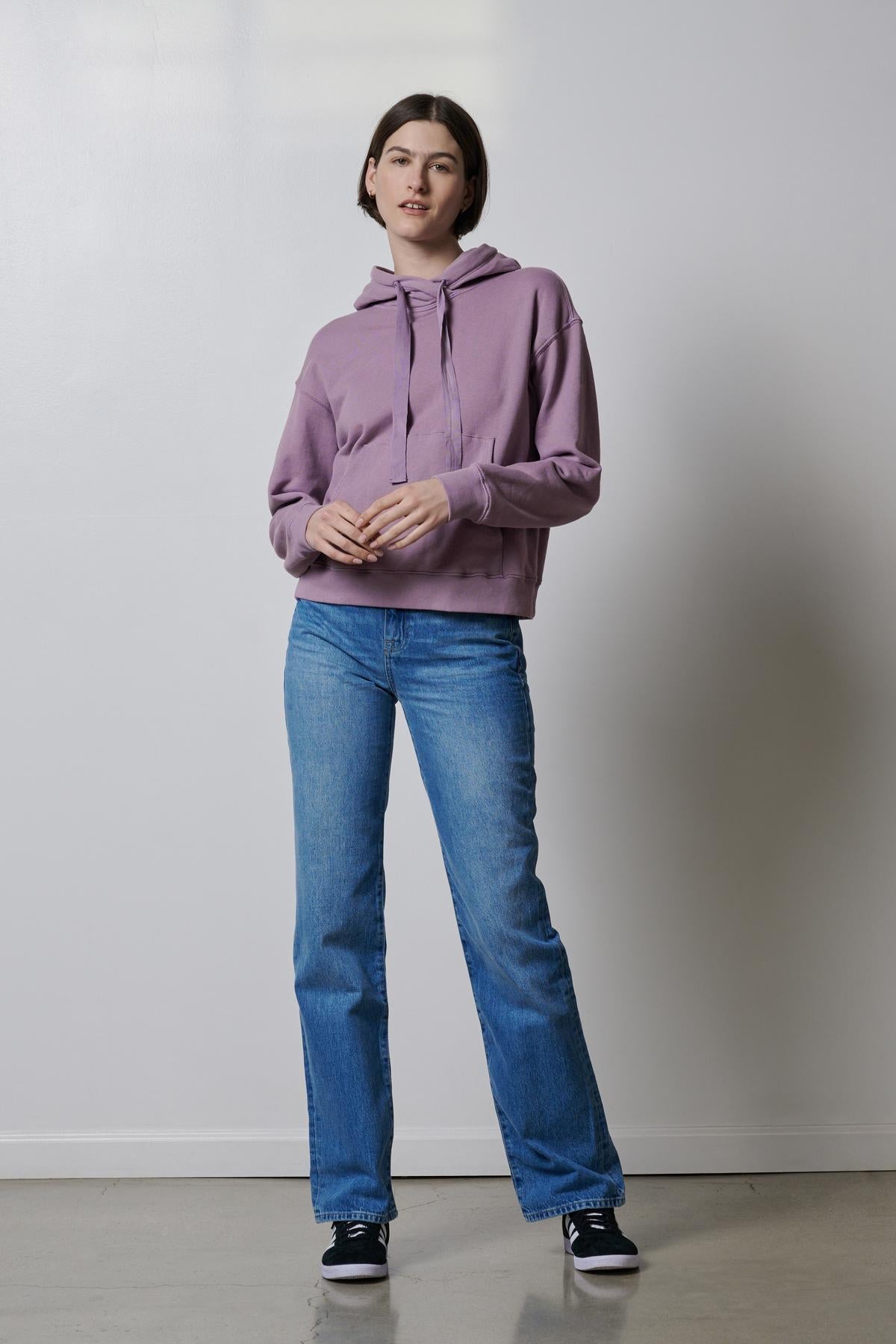   A woman wearing an OJAI HOODIE by Velvet by Jenny Graham and blue jeans. 
