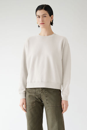 The model is wearing a Velvet by Jenny Graham YNEZ SWEATSHIRT made with organic cotton and olive pants.