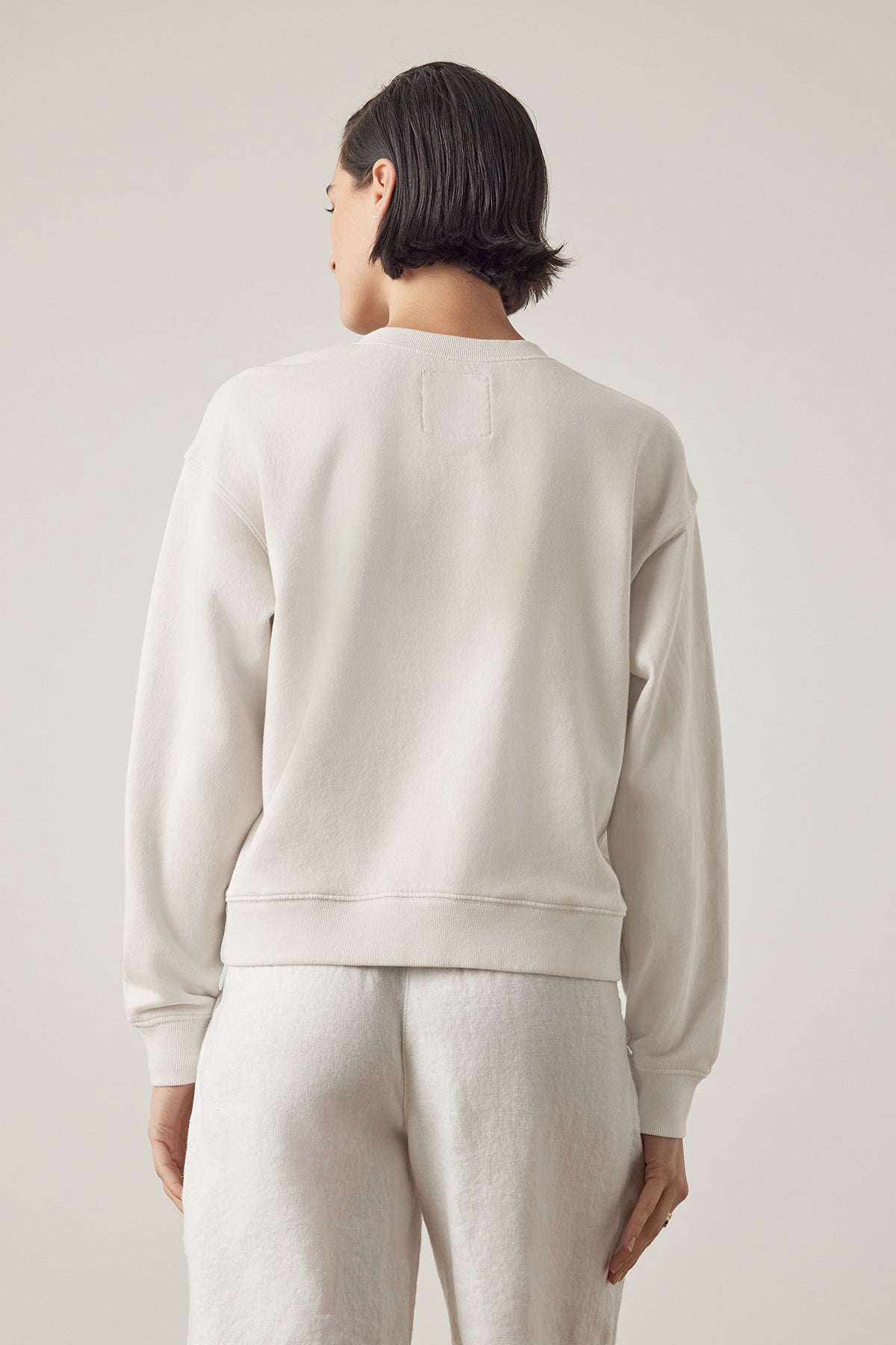   Rear view of a person with short black hair wearing a Velvet by Jenny Graham Ynez sweatshirt and matching pants made of organic cotton, standing against a neutral background. 