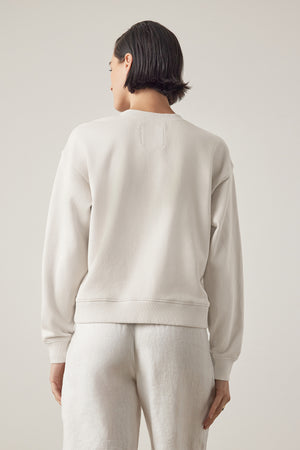 Rear view of a person with short black hair wearing a Velvet by Jenny Graham Ynez sweatshirt and matching pants made of organic cotton, standing against a neutral background.
