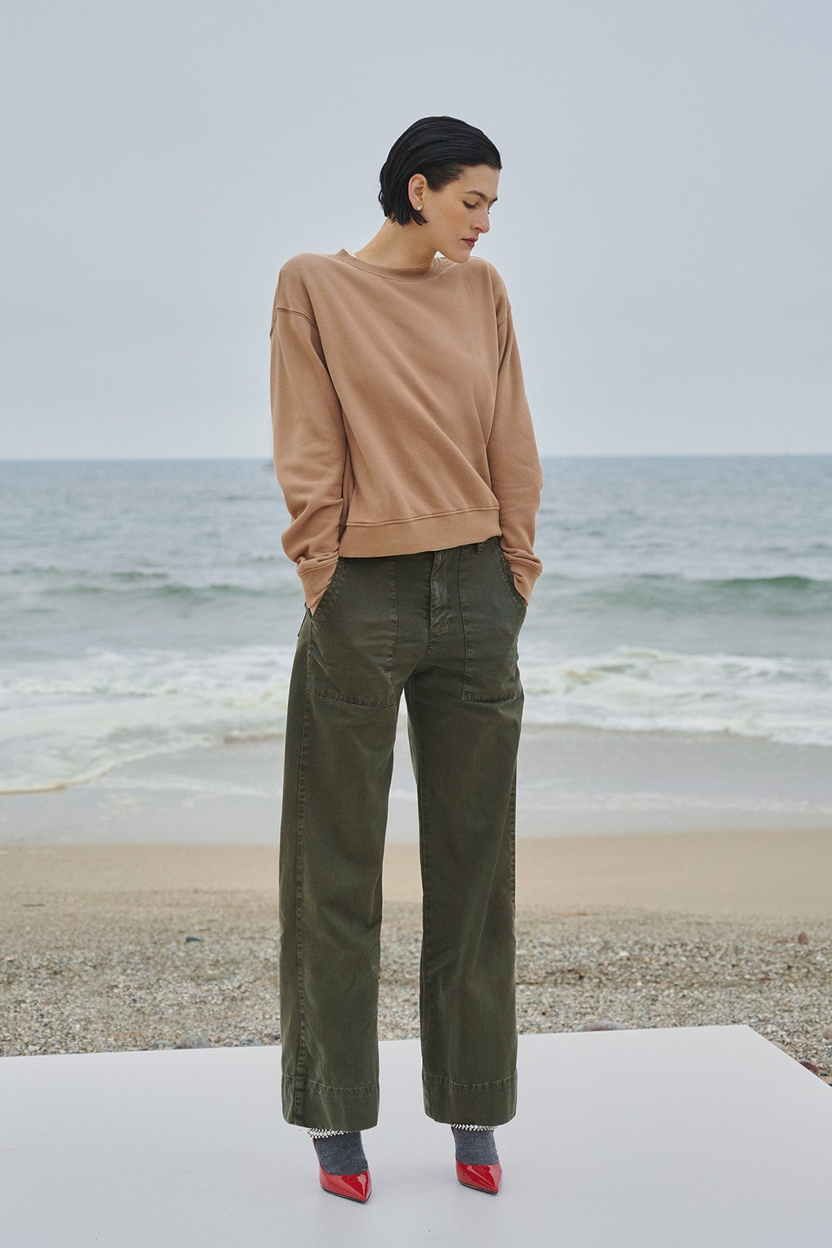 A woman is standing on a beach wearing the Velvet by Jenny Graham YNEZ SWEATSHIRT.-35547465744577