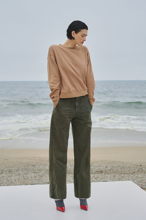 A woman is standing on a beach wearing the Velvet by Jenny Graham YNEZ SWEATSHIRT.
