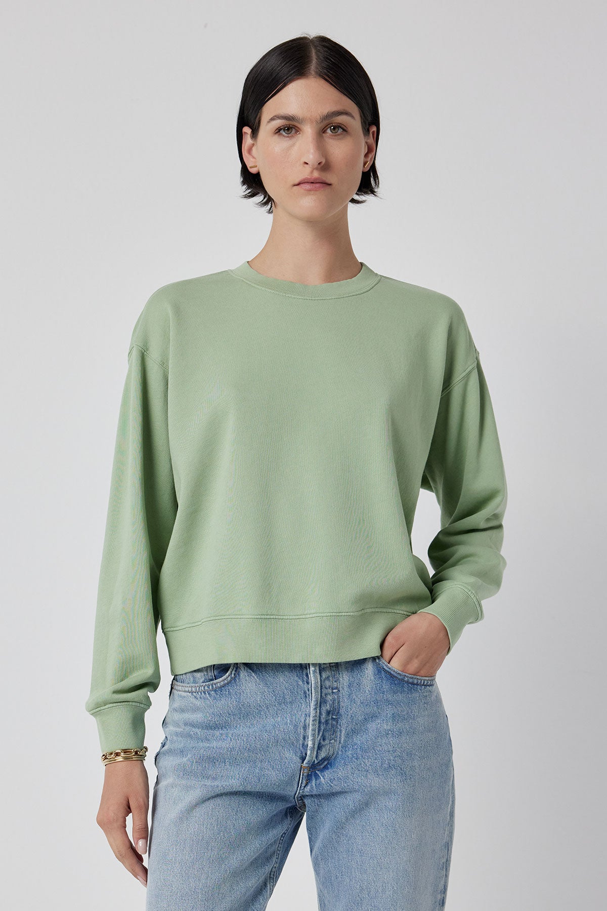   A model wearing a green YNEZ Sweatshirt and jeans made from organic cotton by Velvet by Jenny Graham. 