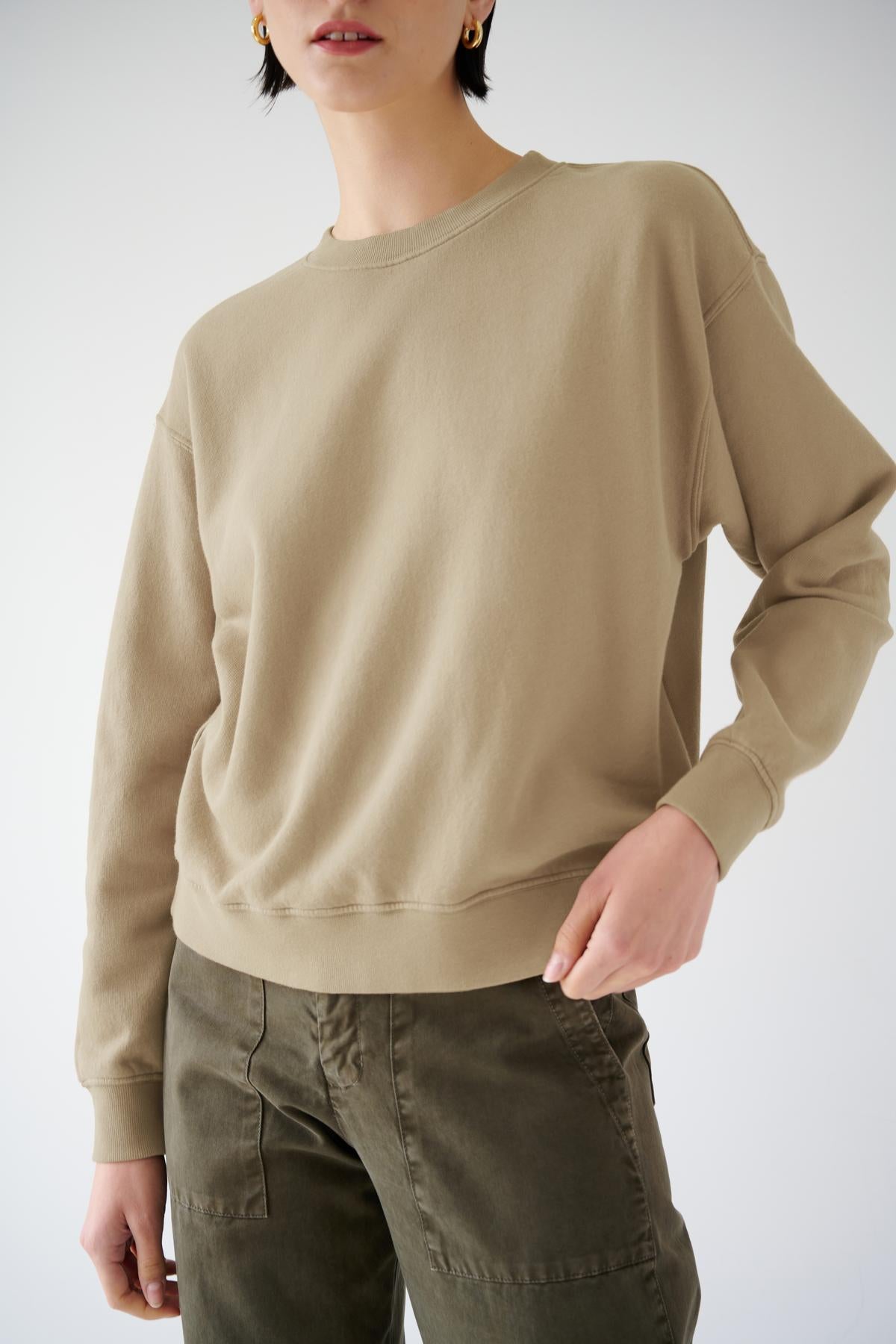 Woman modeling a beige Ynez Sweatshirt from Velvet by Jenny Graham and olive green pants, embodying sustainable fashion.-36463630778561
