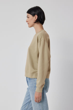 Side profile of a person wearing a Velvet by Jenny Graham Ynez sweatshirt made from organic fleece and blue jeans against a white background.
