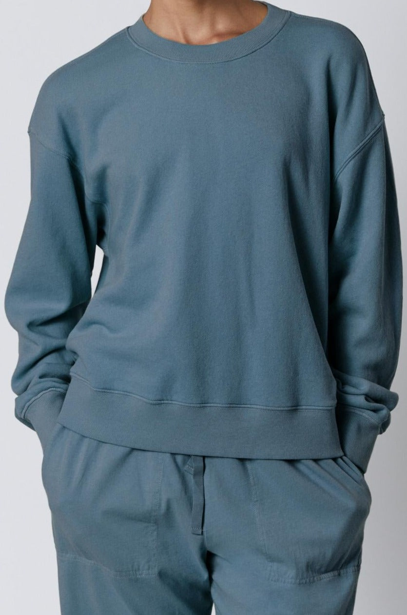 A woman wearing a blue YNEZ Sweatshirt by Velvet by Jenny Graham made of organic cotton and organic fleece.-35721183625409