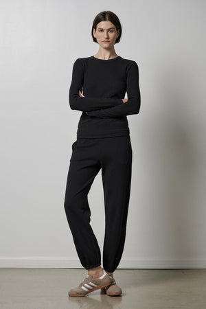 A woman wearing a black long-sleeved top and ZUMA SWEATPANT made from organic cotton. Brand Name: Velvet by Jenny Graham.