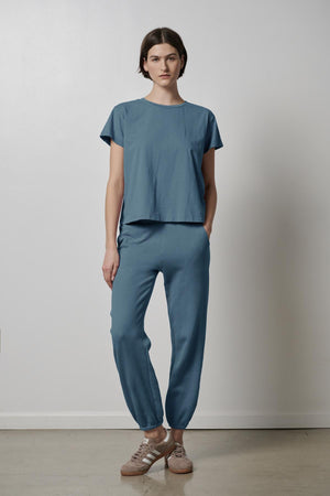 The model is wearing a blue Velvet by Jenny Graham TOPANGA TEE and joggers.