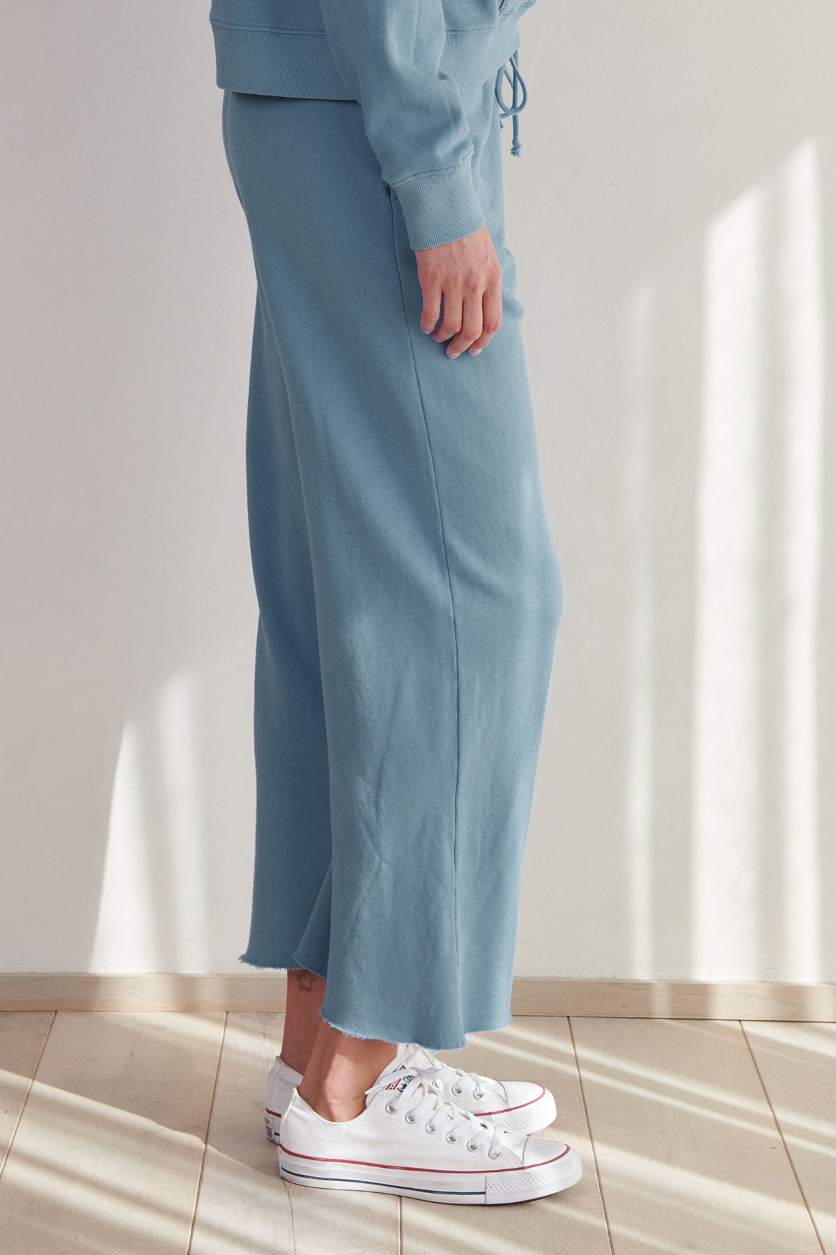   A woman wearing blue Montecito sweatpants by Velvet by Jenny Graham and white sneakers. 