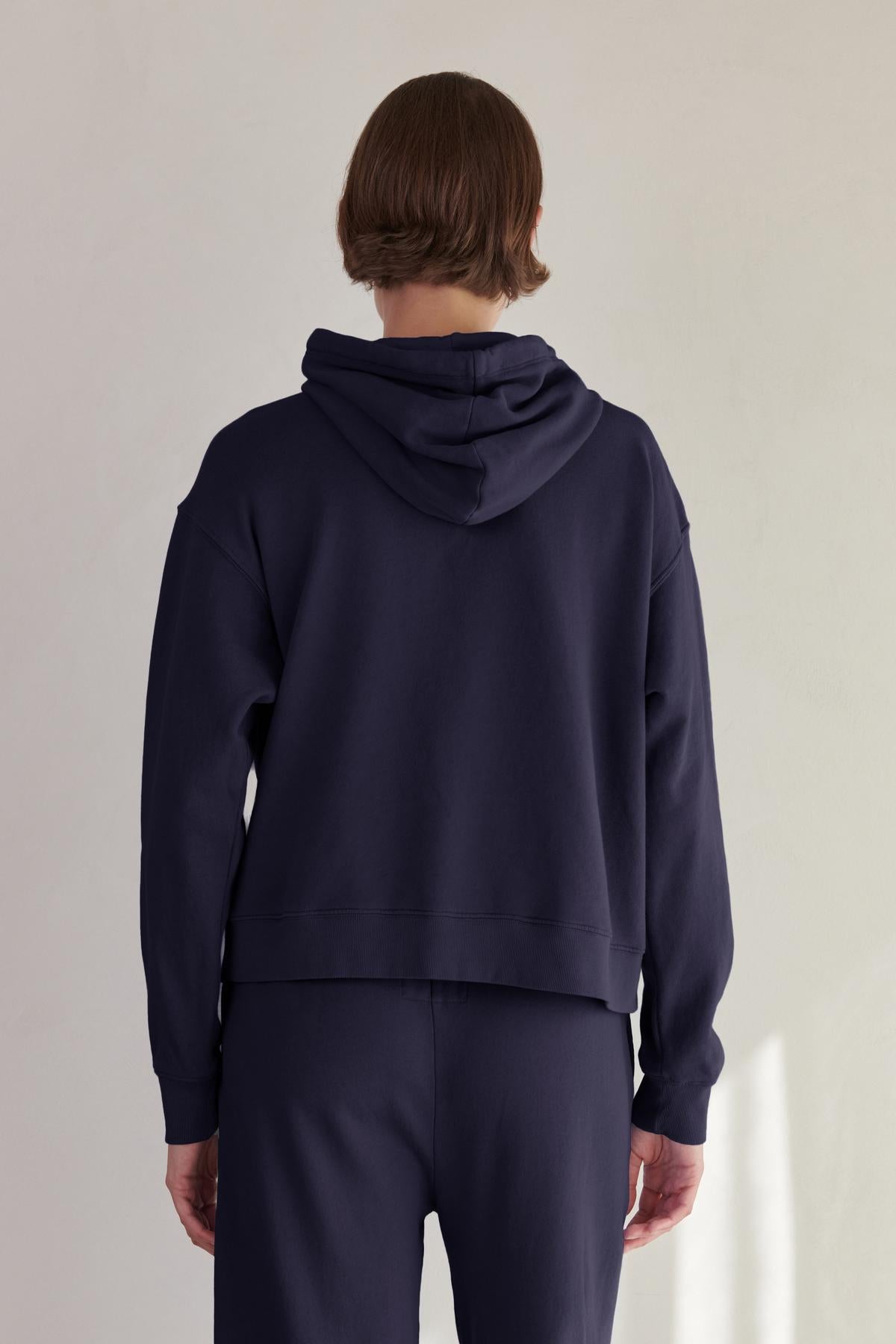   The back view of a woman wearing an Ojai Hoodie made by Velvet by Jenny Graham. 