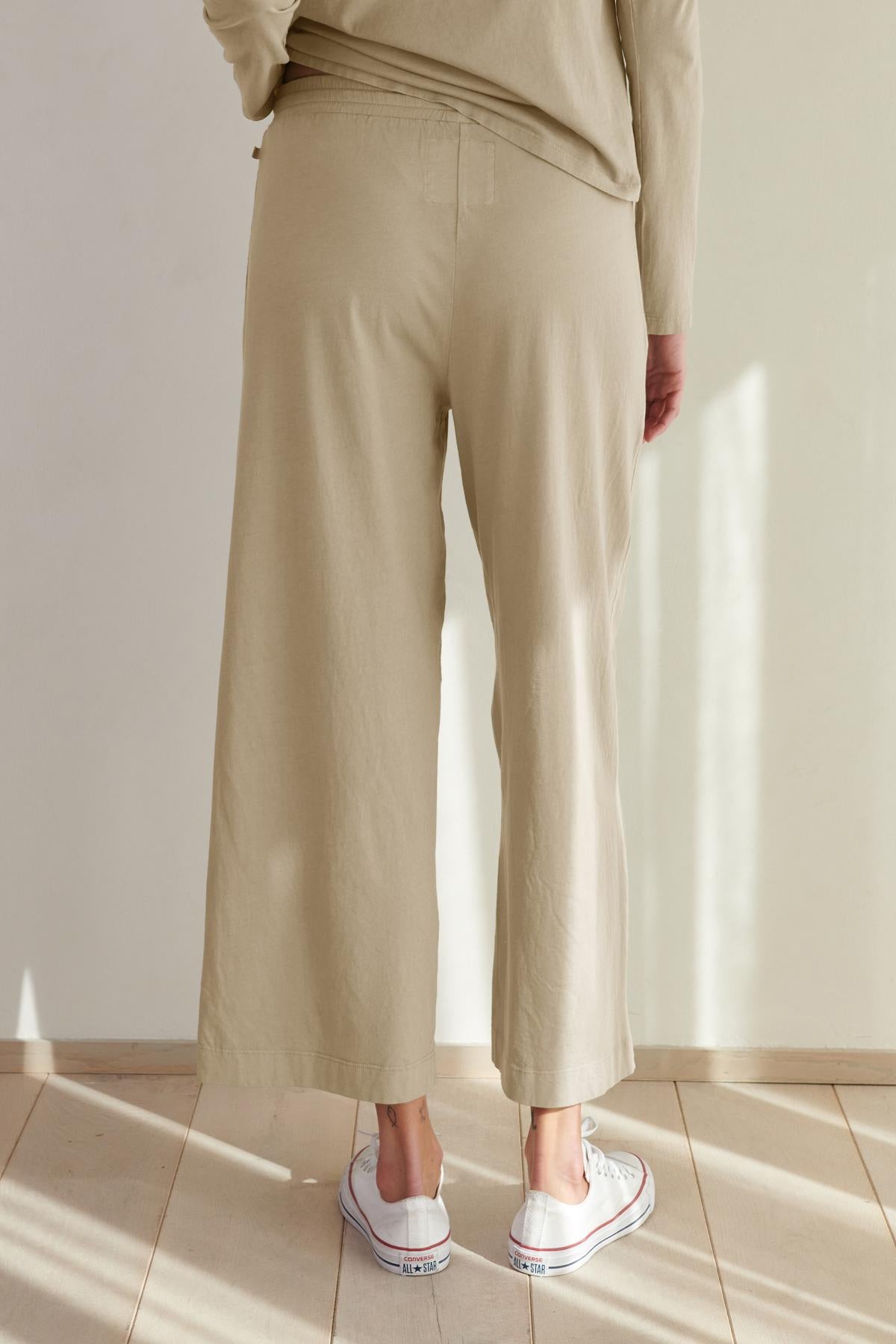   Person standing in a room wearing Velvet by Jenny Graham's PISMO PANT straight leg pants and a matching top with white sneakers. 