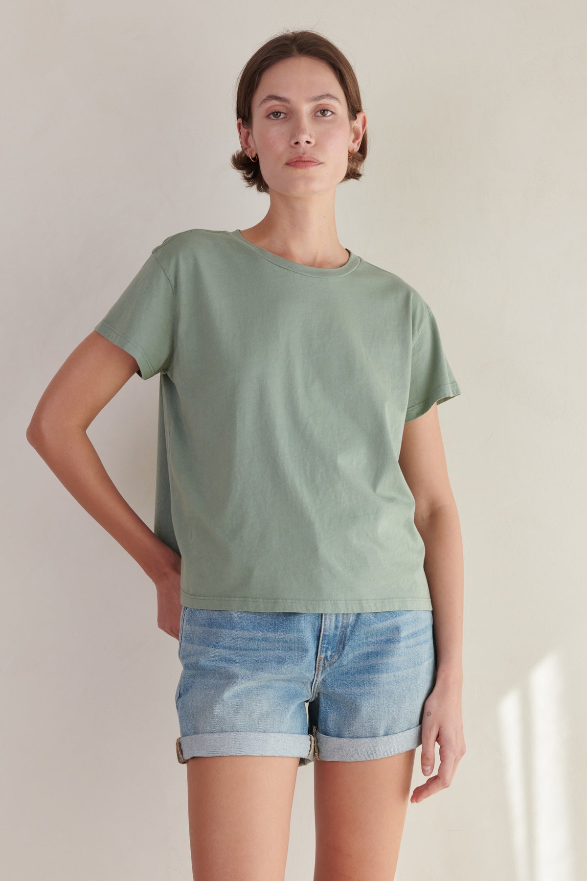 the model is wearing a Velvet by Jenny Graham sage green TOPANGA Tee and denim shorts.-26403955212481