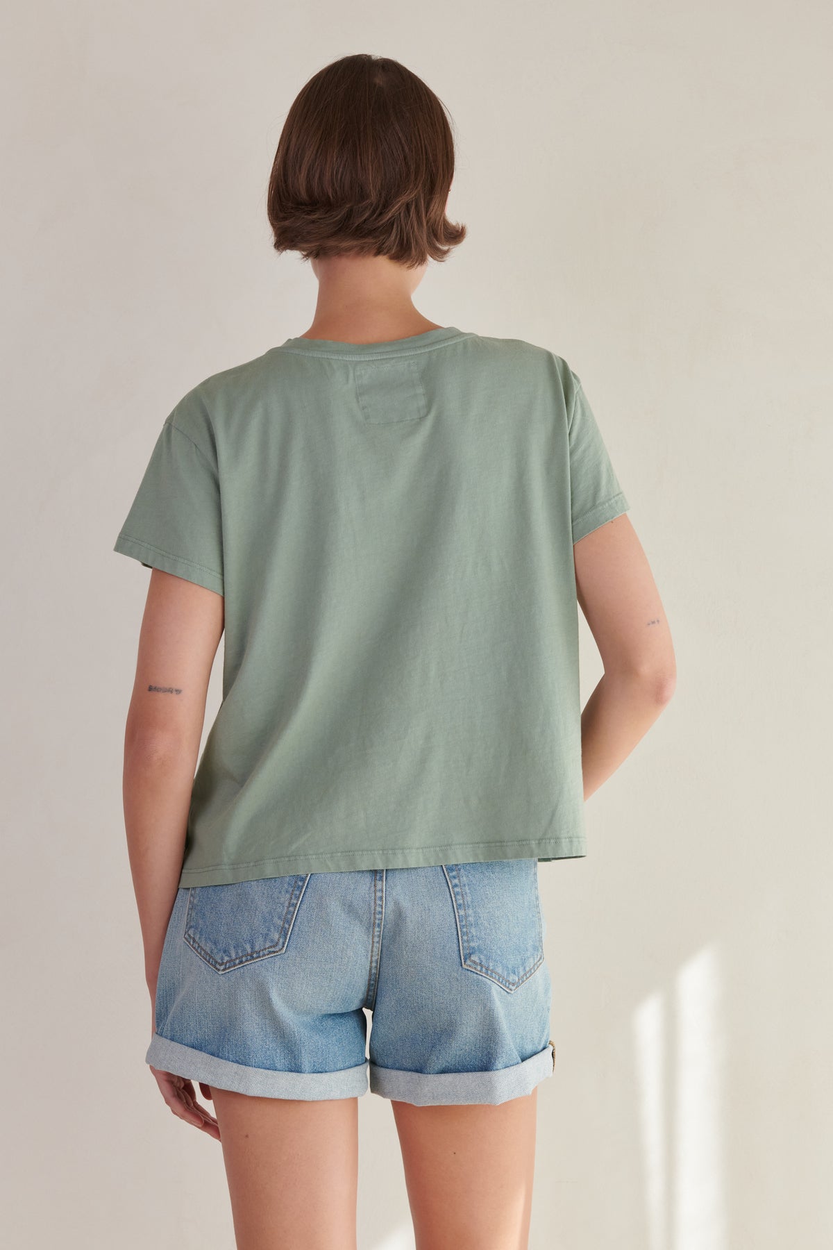 the back view of a woman wearing denim shorts and a Velvet by Jenny Graham TOPANGA TEE.-26403955310785