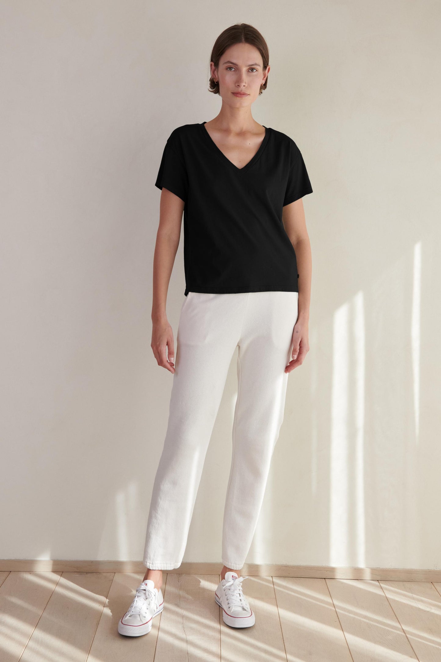 A woman wearing a black VENICE TEE by Velvet by Jenny Graham and white pants.-26560813465793