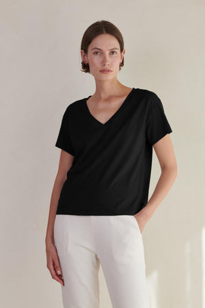 a woman wearing a black VENICE TEE by Velvet by Jenny Graham v - neck t - shirt and white pants.