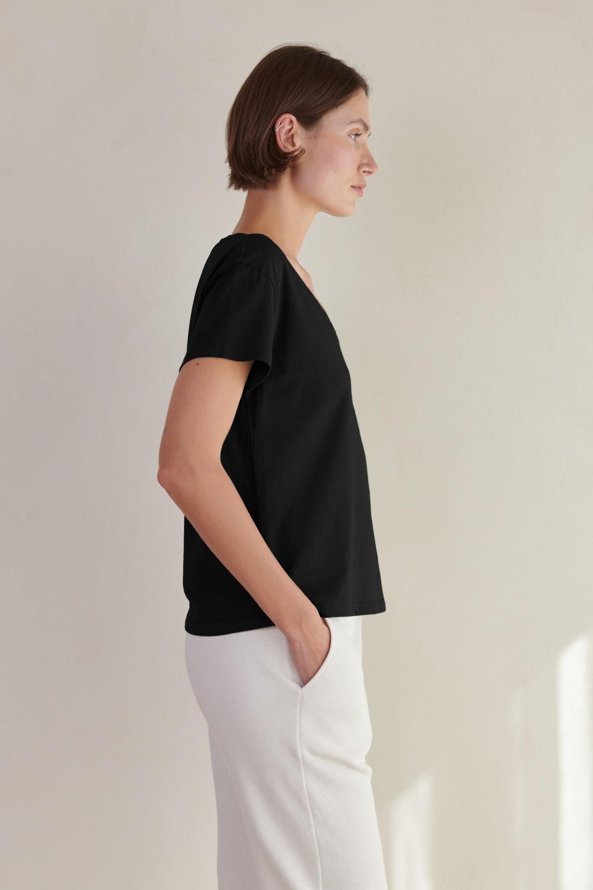 a woman wearing a black Velvet by Jenny Graham VENICE TEE and white pants.-26560813564097