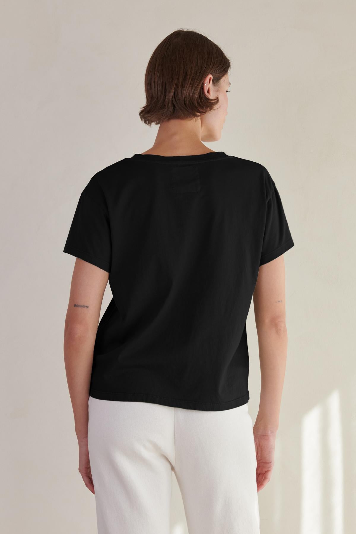 The back view of a woman wearing a Velvet by Jenny Graham VENICE TEE and white pants.-26560813596865