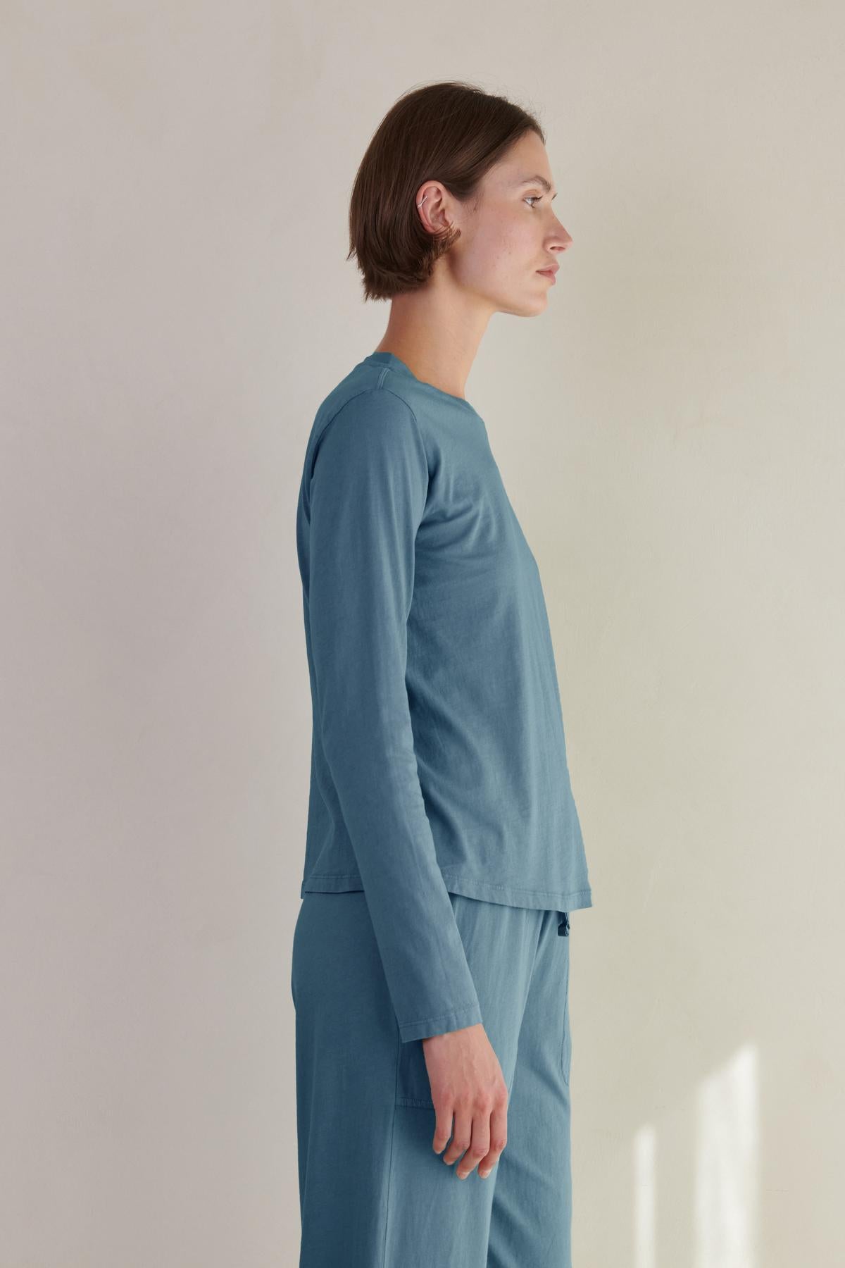The model is wearing a relaxed fit, long-sleeved organic cotton VICENTE TEE in blue from Velvet by Jenny Graham.-35721180152001