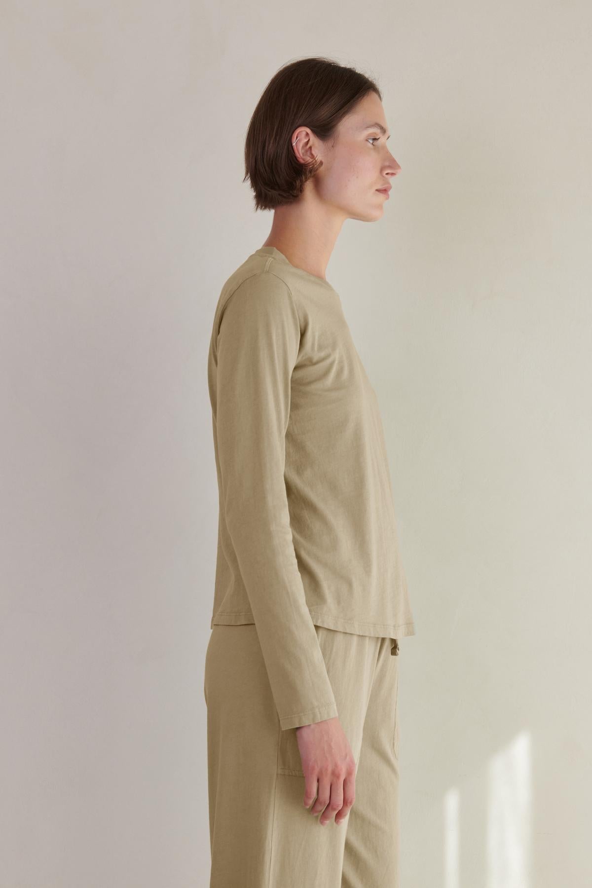   Side profile of a person wearing a Velvet by Jenny Graham VICENTE TEE and matching pants, crafted from organic cotton, against a neutral background. 