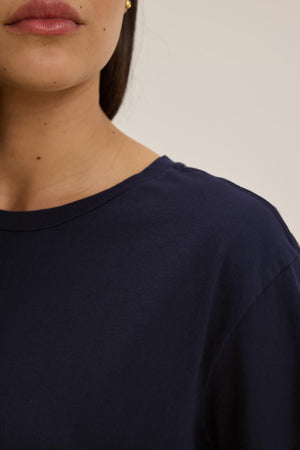 Close-up of the lower half of a woman's face and upper torso, wearing a navy blue TOPANGA TEE by Velvet by Jenny Graham.