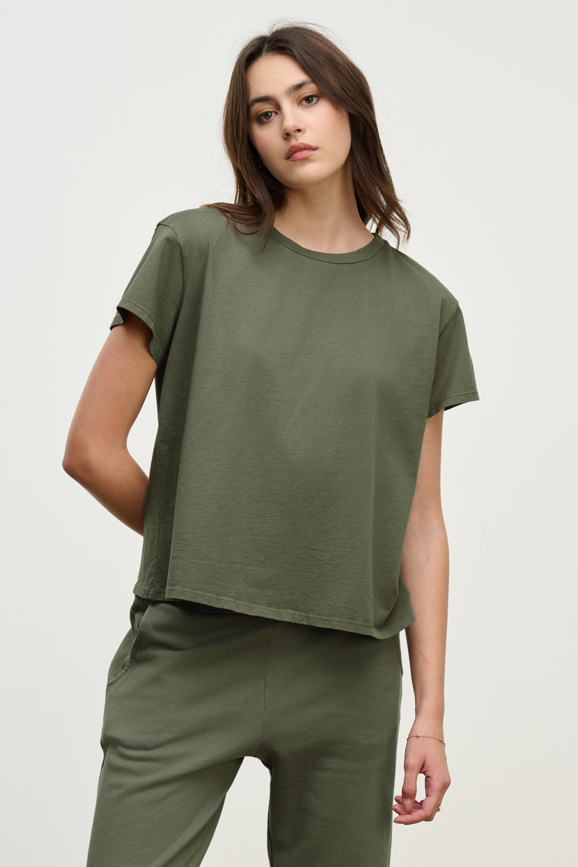 A person wearing a relaxed-fit Olive TOPANGA TEE by Velvet by Jenny Graham and pants, crafted from organic cotton, stands against a plain background.