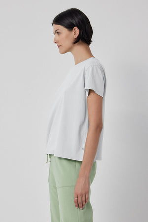 The model is wearing a white Velvet by Jenny Graham TOPANGA TEE and green sweatpants.