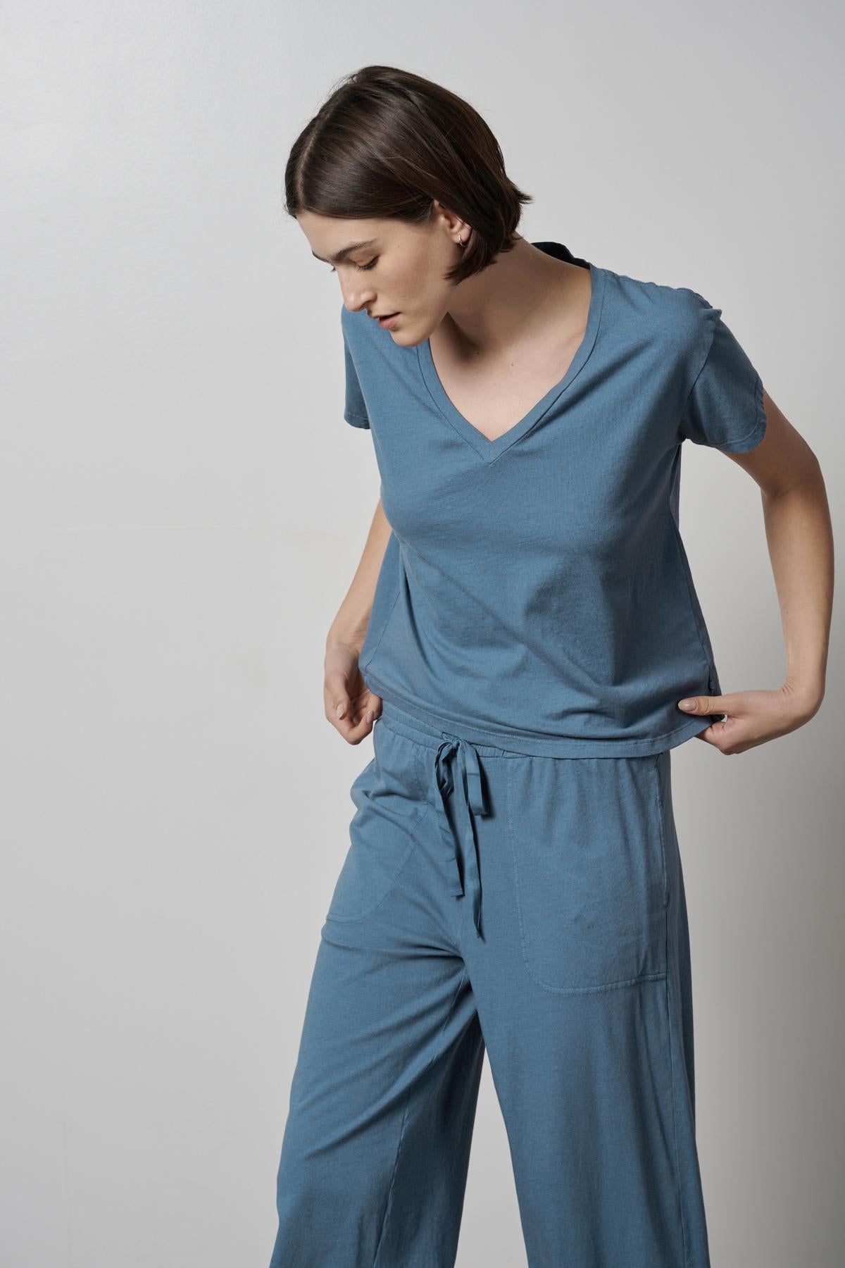 A woman wearing a blue Velvet by Jenny Graham VENICE TEE with organic cotton wide leg pants, showcasing the relaxed fit and 90s silhouettes.-35495940849857