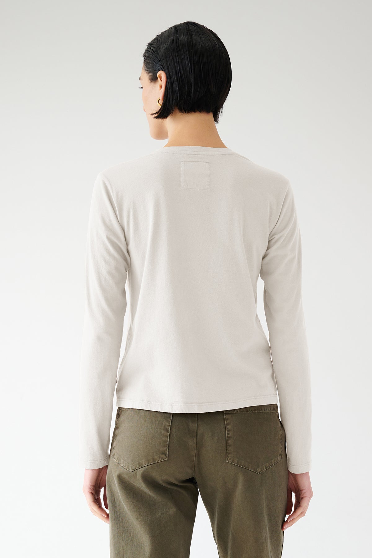 A person wearing a VICENTE TEE made from organic cotton and green pants, viewed from behind, embodying seasonless dressing by Velvet by Jenny Graham.-36503793598657