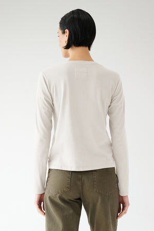 A person wearing a VICENTE TEE made from organic cotton and green pants, viewed from behind, embodying seasonless dressing by Velvet by Jenny Graham.