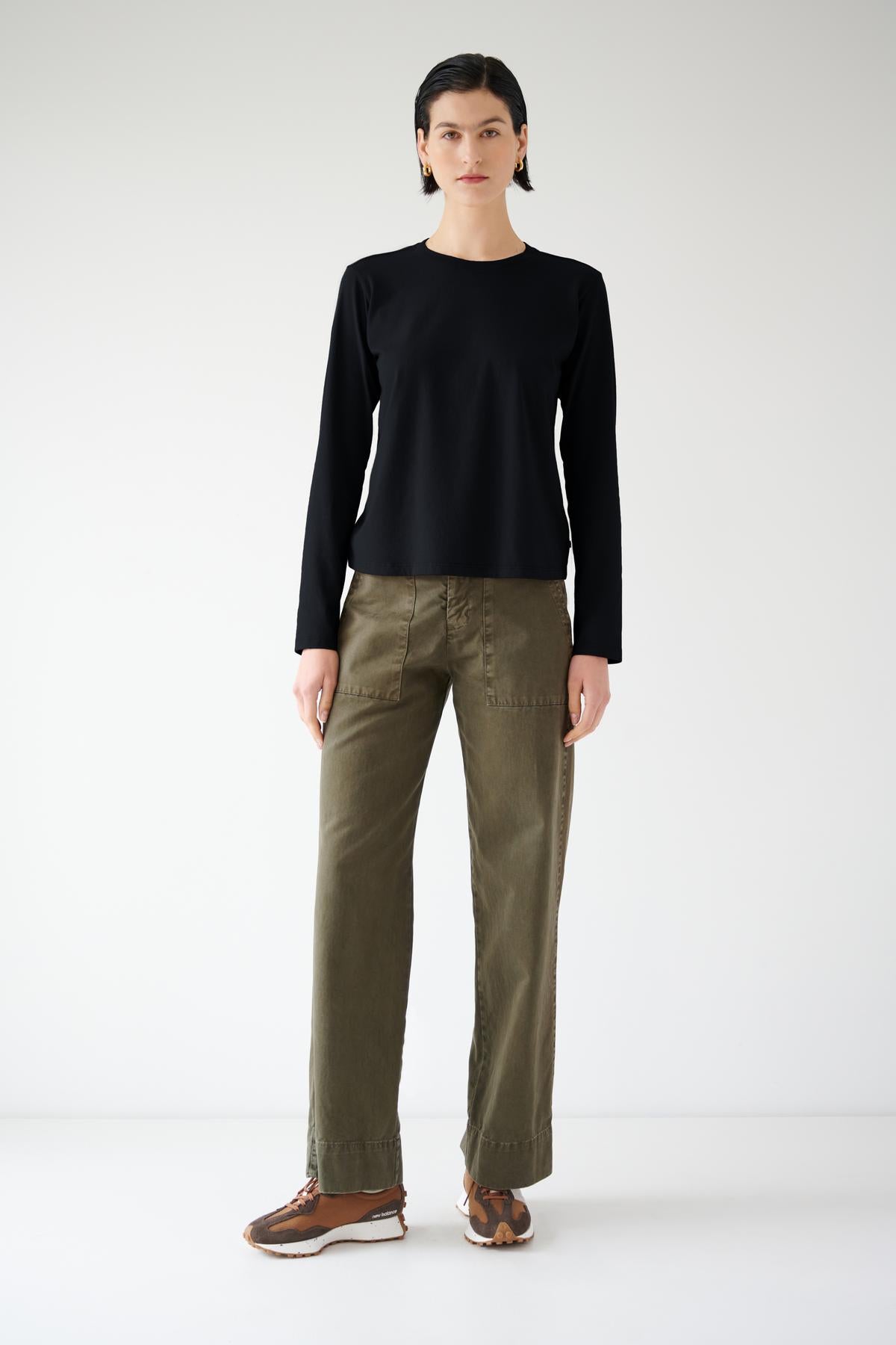   A woman wearing a Velvet by Jenny Graham VICENTE TEE, a relaxed fit black top, and organic cotton green pants, showcasing seasonless dressing. 