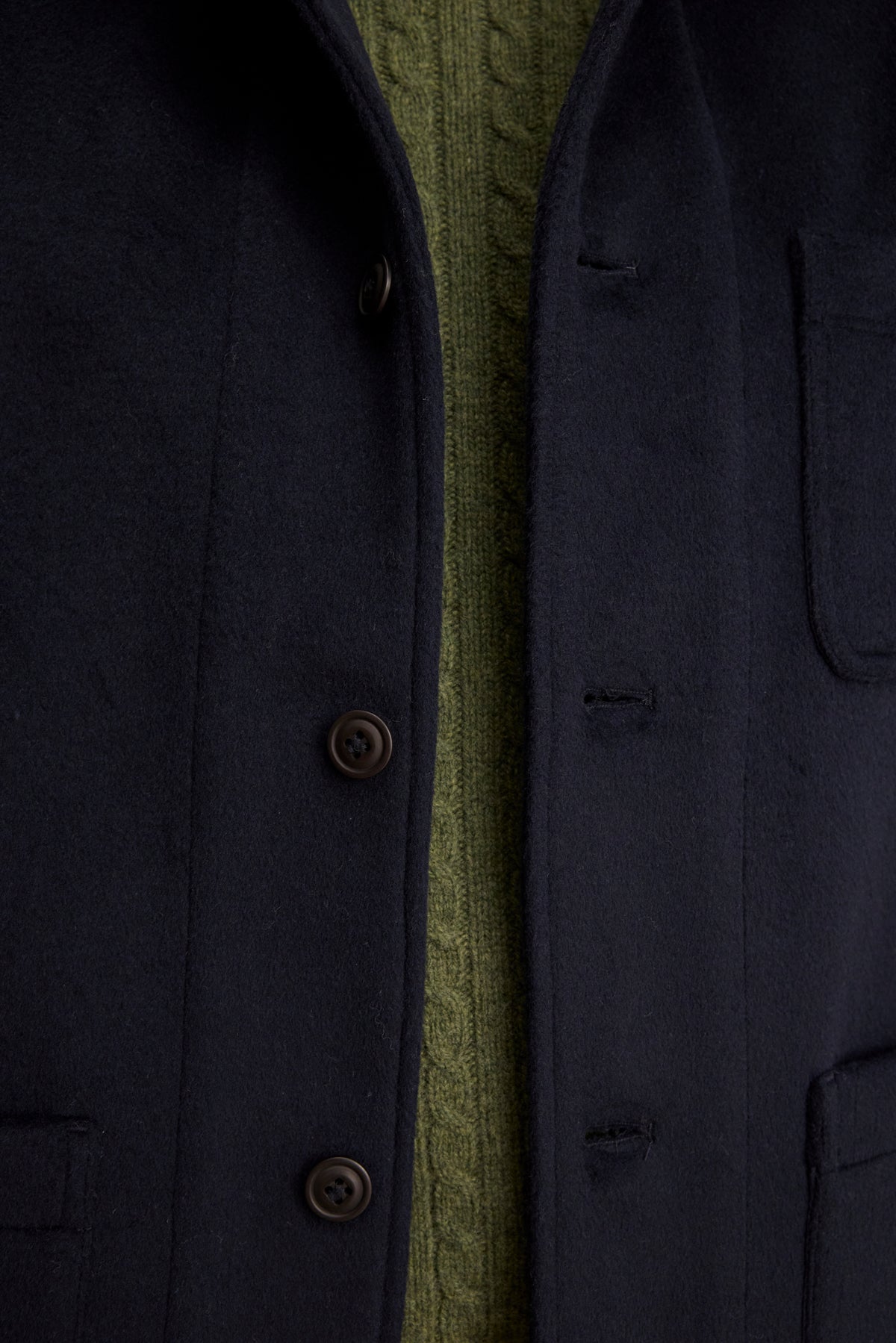 Close-up of the EMERSON CHORE JACKET by Velvet by Graham & Spencer, a black wool blend style, buttoned and layered over a green cable-knit sweater—ideal for everyday wear.-39934406262977