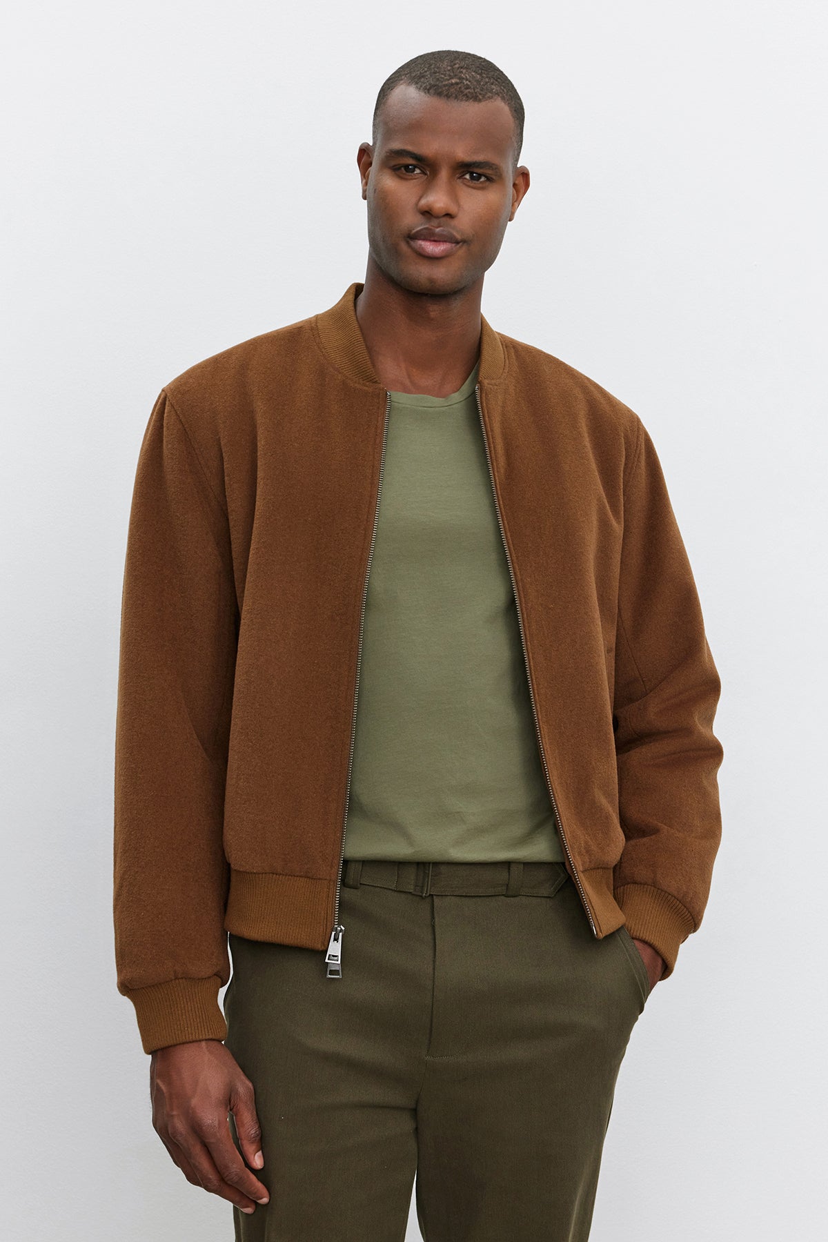   A man wearing a Velvet by Graham & Spencer FRAZIER BOMBER JACKET in a brown wool blend over a green shirt stands in front of a plain background. 