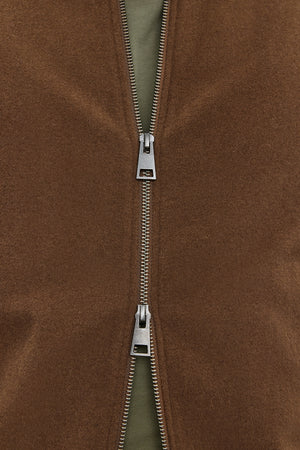 Close-up of a partially unzipped FRAZIER BOMBER JACKET by Velvet by Graham & Spencer, revealing a green inner layer. The silver-colored zipper boasts a prominent mechanism, while the wool blend ensures lasting warmth.