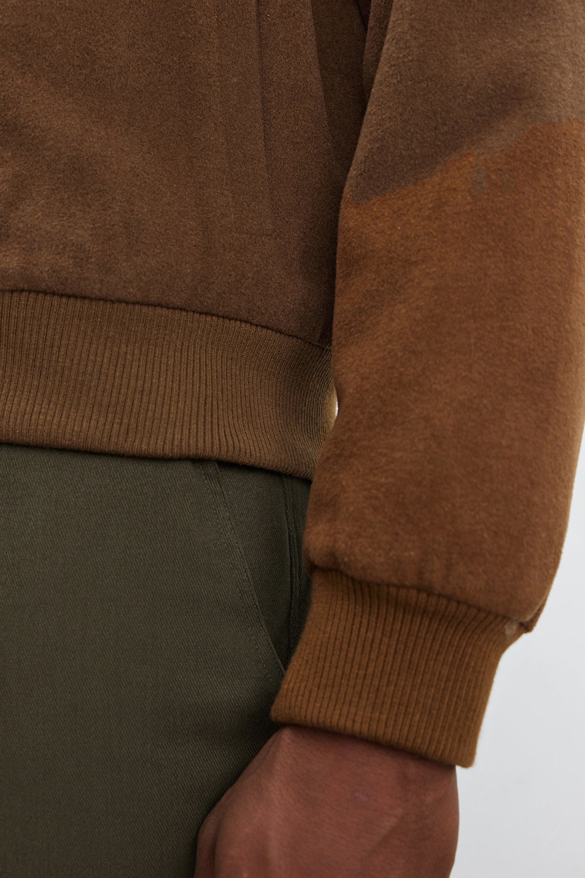 Close-up of a person's arm and torso wearing olive green pants and the Velvet by Graham & Spencer FRAZIER BOMBER JACKET, a brown long-sleeved wool blend shirt with ribbed cuffs, showcasing lasting warmth.-37893890048193