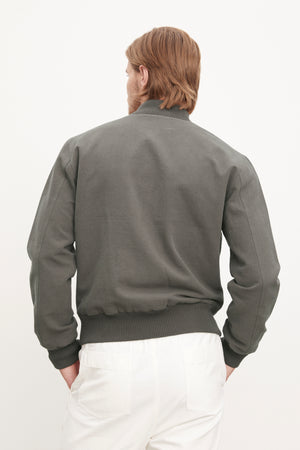 The back of a man wearing a Velvet by Graham & Spencer Garner Linen Blend Bomber Jacket and white pants.