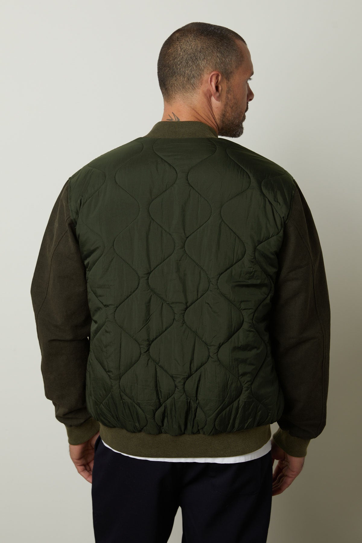   The back view of a man wearing a Velvet by Graham & Spencer MAISON quilted jacket that combines style and functionality. 