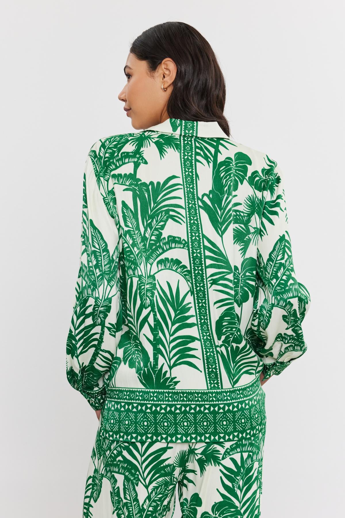   Woman seen from the back wearing a white and green palm print AYLA BUTTON-UP SHIRT with long sleeves, standing against a plain background. Brand name: Velvet by Graham & Spencer 