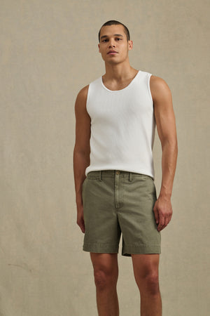 A man stands against a plain background wearing a white tank top and Velvet by Graham & Spencer JOEL SHORT in olive green cotton twill, facing forward with a neutral expression.