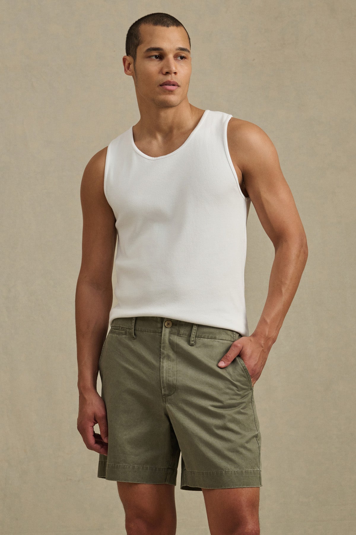 A man in a white sleeveless tank top and JOEL SHORT from Velvet by Graham & Spencer, featuring cotton twill fabric and 5-pocket styling, stands with one hand in his pocket against a neutral background.