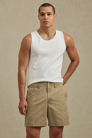 A man wearing a white sleeveless shirt and the JOEL SHORT by Velvet by Graham & Spencer, a classic 5-pocket cotton twill short, stands facing the camera against a plain beige background.